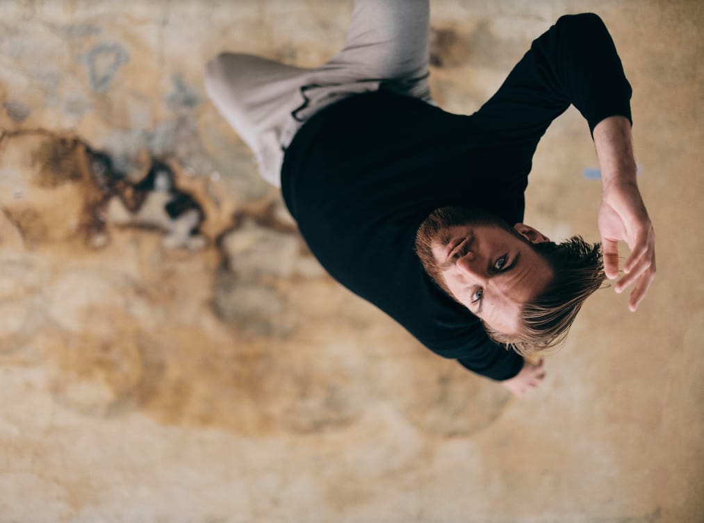 Close-up portrait of Jean Camenen from an upside-down perspective against a cracked wall
